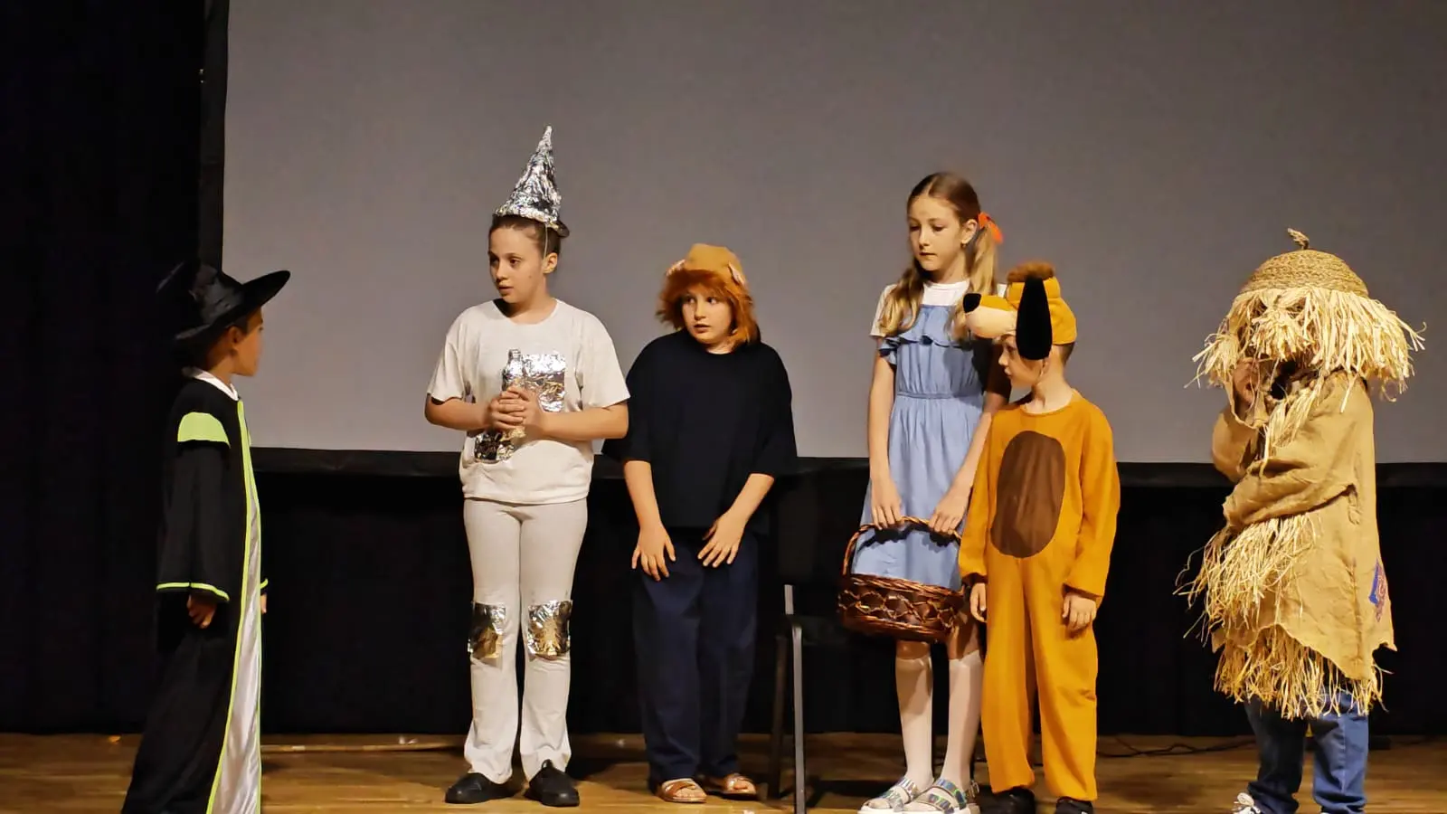 Distribuție în costume inspirate din „Vrăjitorul din Oz”, aliniată pe scenă