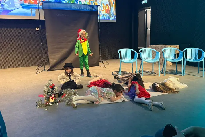 Un elev în costum verde, pe scenă, alături de personajele adormite