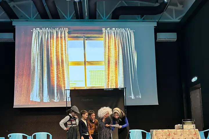 Scenă cu decor de fereastră proiectat și grupul de actori în plan îndepărtat